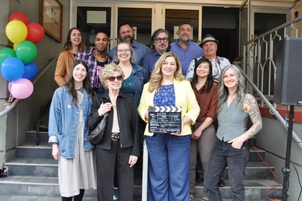 NCTS team members on the theatre steps, holding a clapperboard